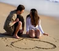 Couple on a beach with a heart drawn in the sand
