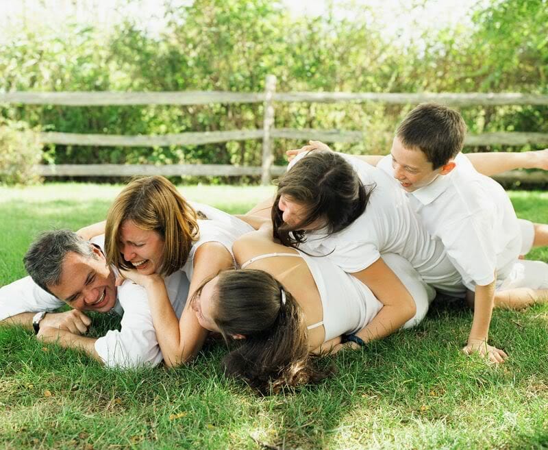 Parents and kids rolling on the grass laughing