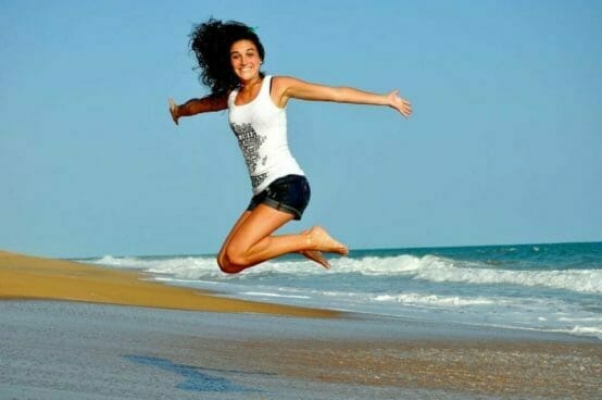 Happy woman jumping in the air on a beach