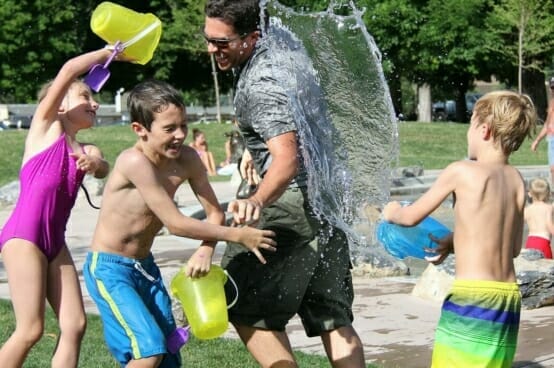 Kids having a water fight with a parent